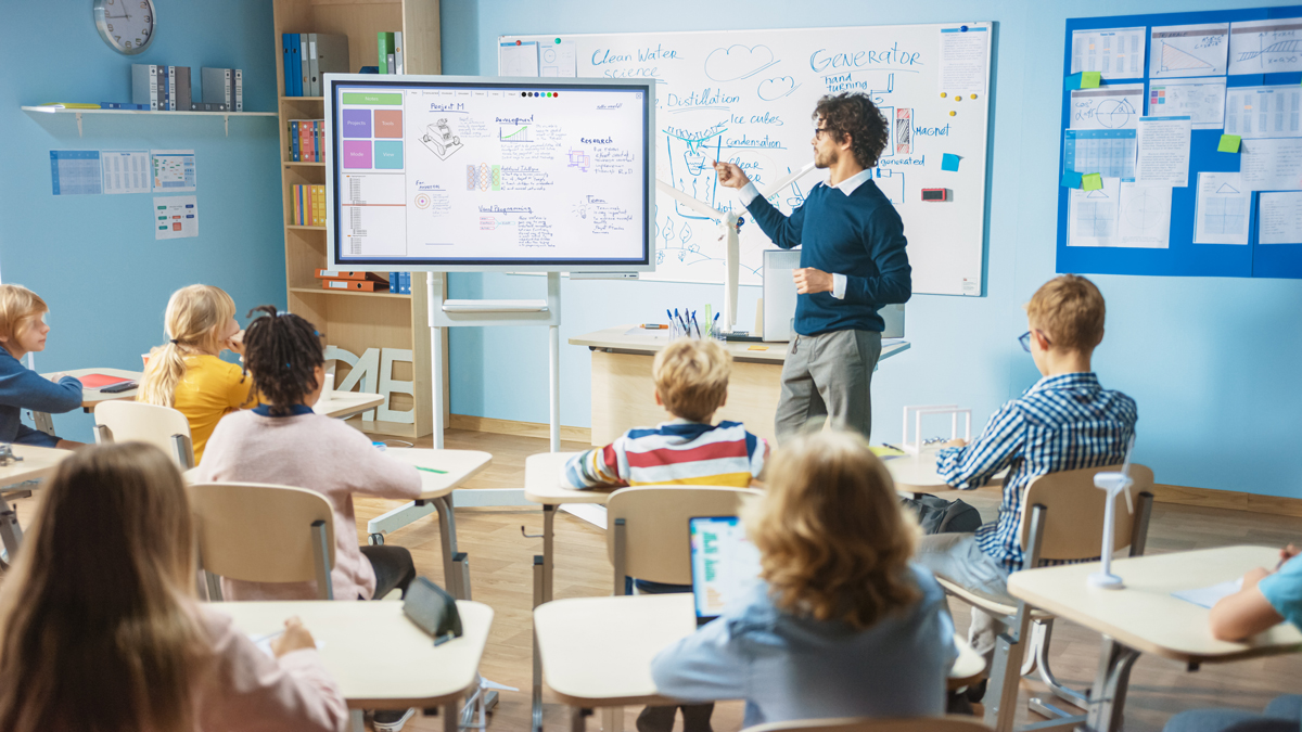 Lehrer erklärt Schülerinnen und Schülern an der Flip Chart Tafel Maschinentechnik