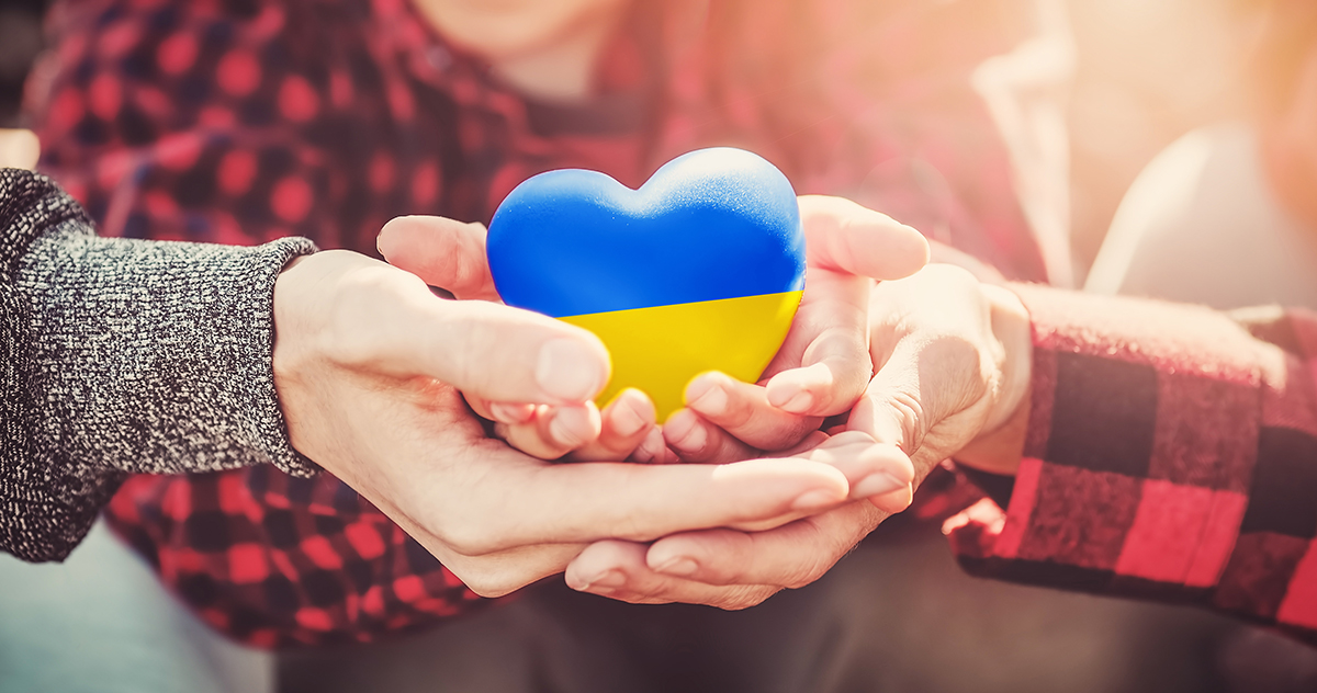 Hände halten ein Herz in ukrainischen Farben