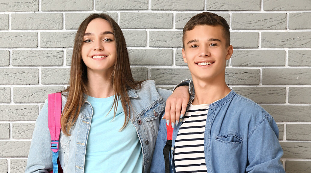 Junge und Mädchen stehen zusammen vor einer Wand.