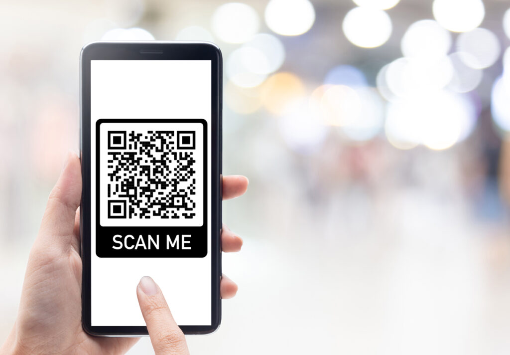 Hand mit Mobiltelefon scannt Qr-Code auf dem Hintergrund des Einkaufszentrums.