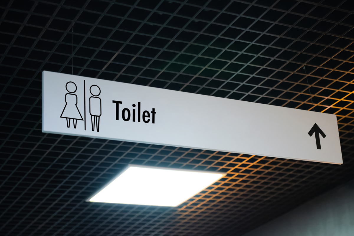 Öffentliches Toilettenschild mit Toilettensymbol und Richtungspfeil