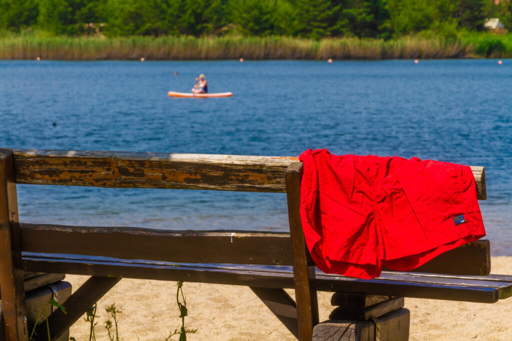 Badesee Dixförda - Bank mit roter Badehose und Blick auf dem See