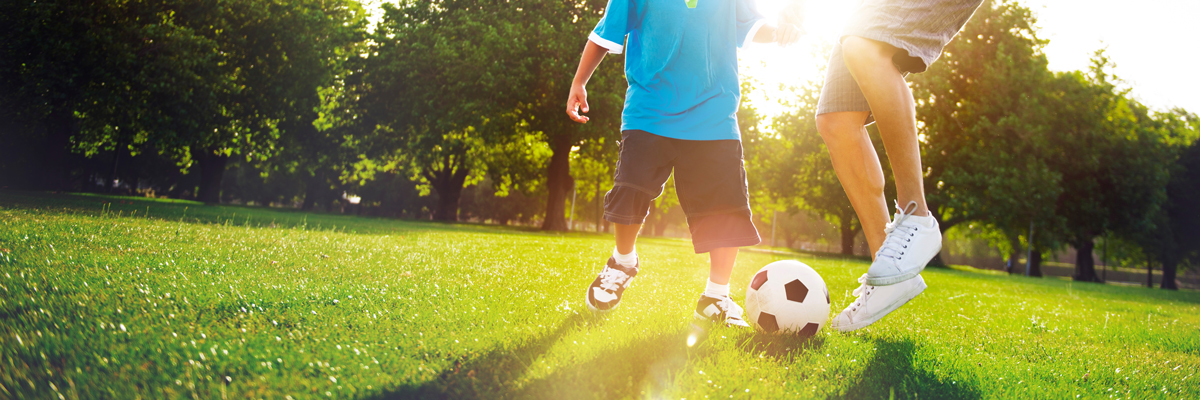 Kleiner Junge, der mit seinem Vater Fußball spielt