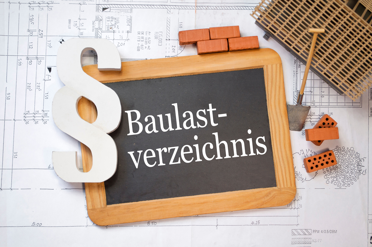 Auf einen Baulplan liegt ein Schild mit der Aufschrift Baulastverzeichnis. Daneben liegen Ziegelsteine, eine Schaufel und das Symbol einen Paragraphen.