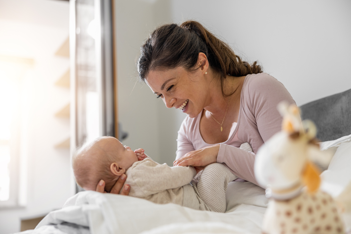 Mutter, die mit ihrem drei Monate alten Baby im Schlafzimmer spielt