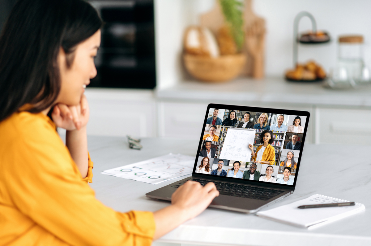 Junge Frau schaut auf einen Laptop, wo ein Online-Seminar zu sehen ist