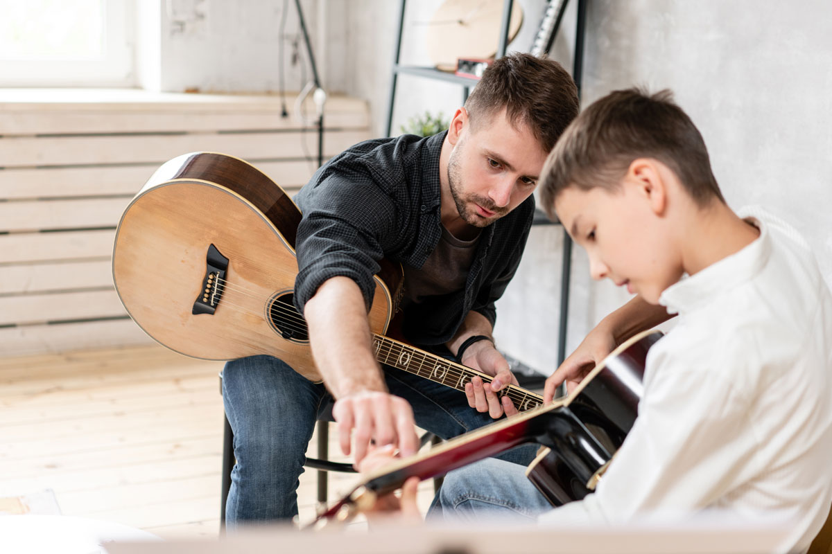 Lehrer bringt Schüler Gitarre spielen bei