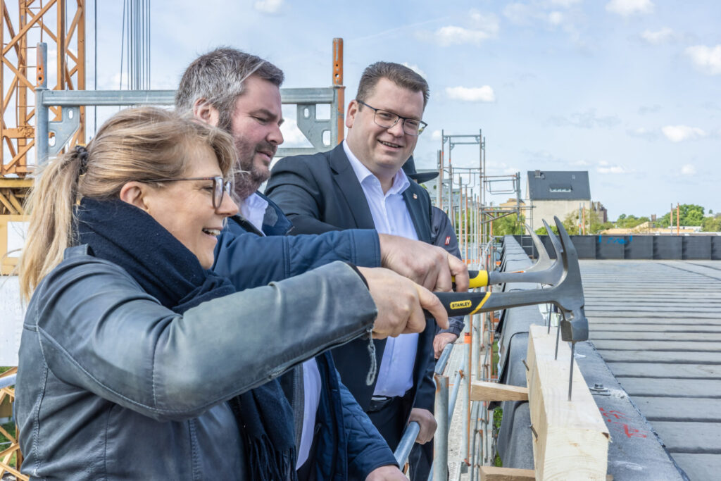 Der symbolische letzte Nagelschlag von Landrat Christian Tylsch (re.) mit dem Kreistagsvorsitzenden Enrico Schilling (Mitte) und Archivleiterin Ines Kluge beim Richtfest des Kreisarchivs der Kreisverwaltung Wittenberg.