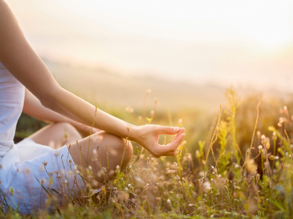 Frau macht Yoga-Übung auf der Wiese
