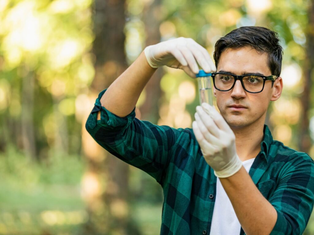 Person prüft entnommene Probe aus dem Wasser