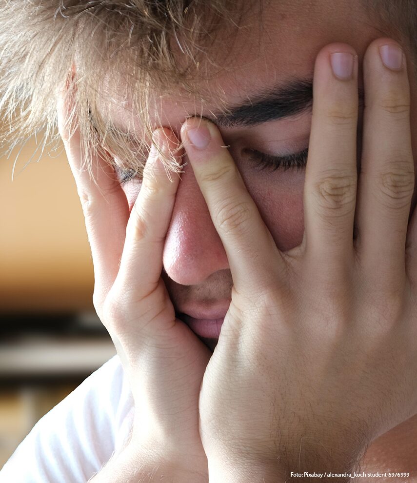 Teenager stützt Gesicht in seine Hände