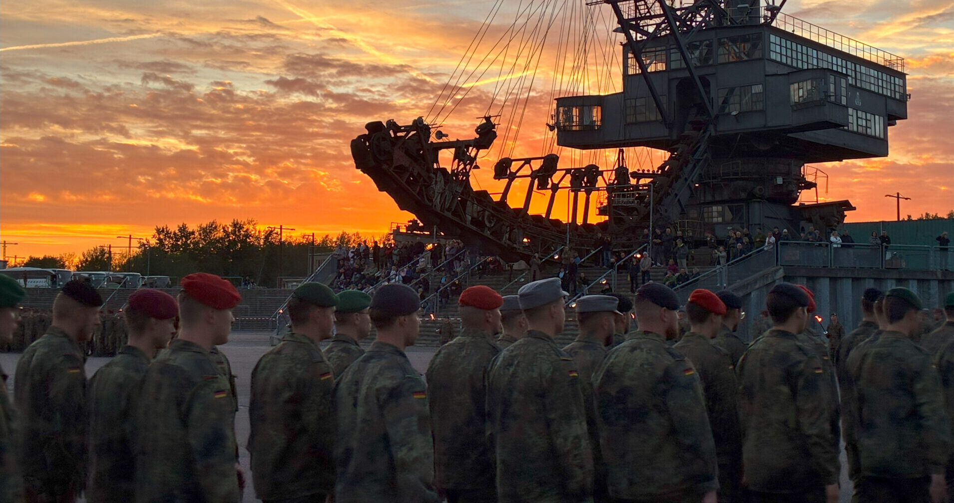 Eine Gruppe von unteroffizieren läuft ein. Im Hintergrund ist ein großer Bagger zusehen. Es ist Abendstimmung.