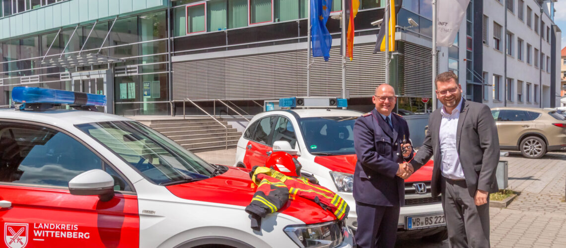 Oliver Hoppe und Christian Tylsch schütteln sich, vor Feuerwehrautos stehend, die Hände.