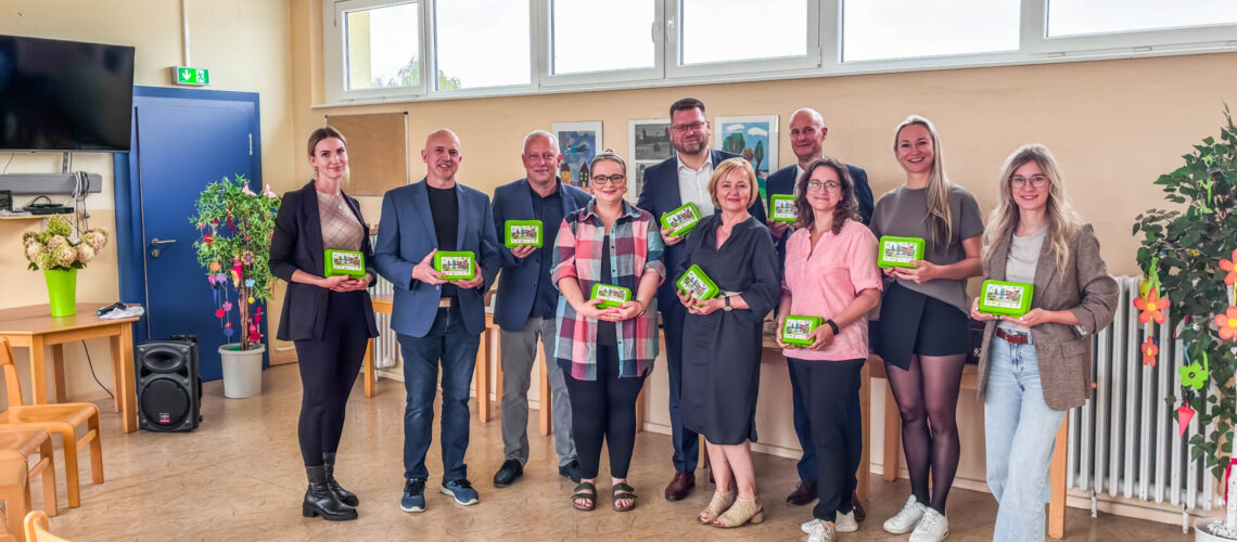 Eine Gruppe von Menschen steht in einem Klassenraum und präsentiert die Bio-Brotbox.