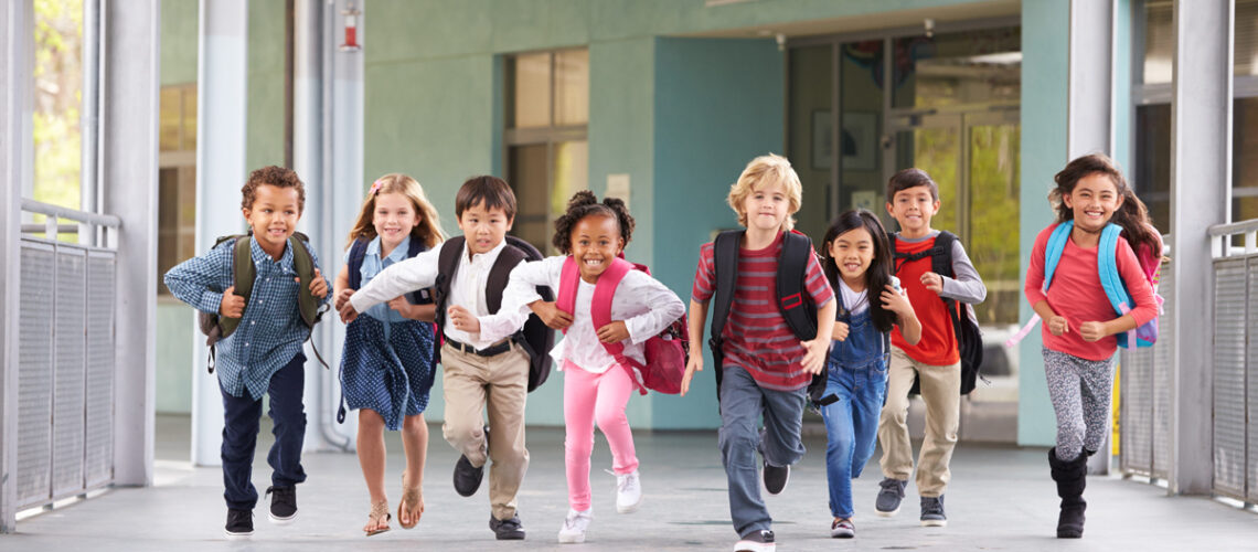 Gruppe von Grundschulkindern, die in einem Schulkorridor laufen