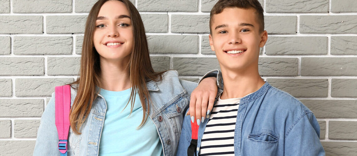 Junge und Mädchen stehen zusammen vor einer Wand.