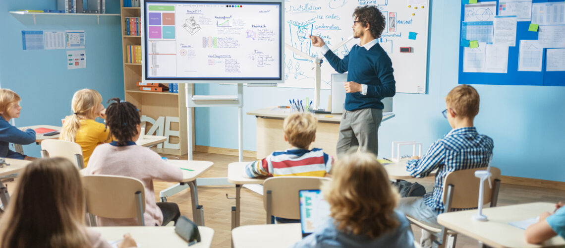 Lehrer erklärt Schülerinnen und Schülern an der Flip Chart Tafel Maschinentechnik