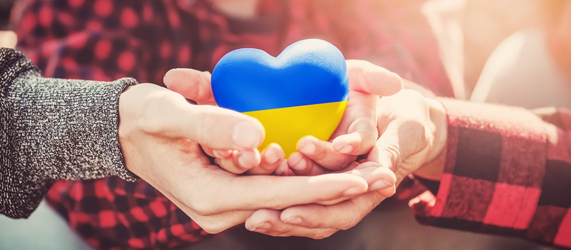Hände halten ein Herz in ukrainischen Farben
