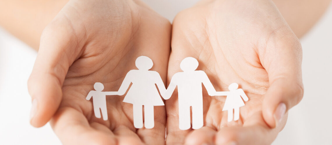 Frauenhände mit Papiermannfamilie