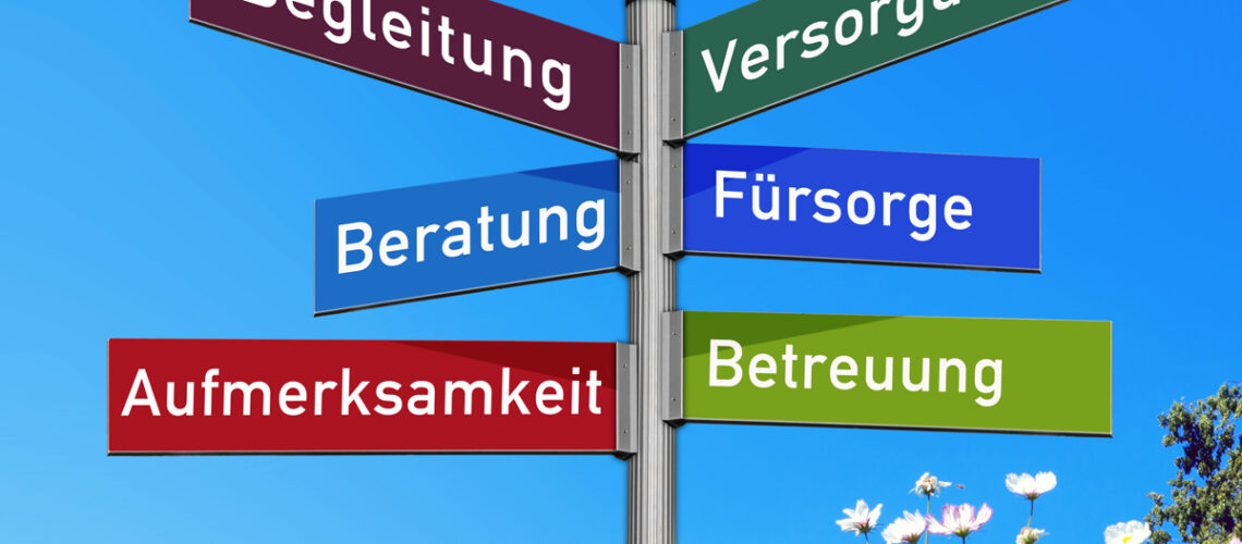 Wiese mit Straßenverkehrsschild mit den Wörtern Begleitung, Versorgung, Beratung, Fürsorge, Aufmerksamkeit, Betreuung