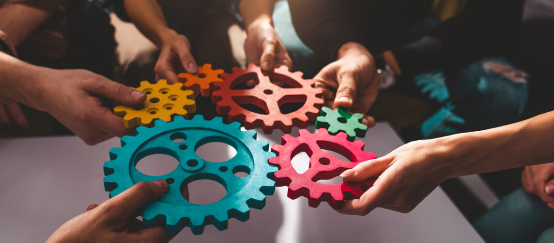 Teamwork von Geschäftsleuten arbeitet zusammen und kombiniert Zahnräder