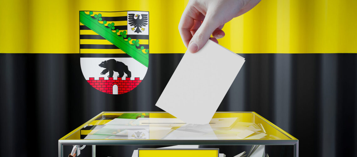 Landtagswahlen Sachsen-Anhalt - Wappen im Hintergrund und davor eine Wahlurne