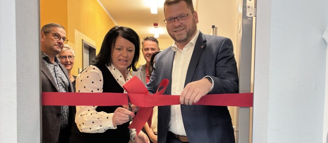 ein Mann und eine Frau zerschneiden ein rotes Band