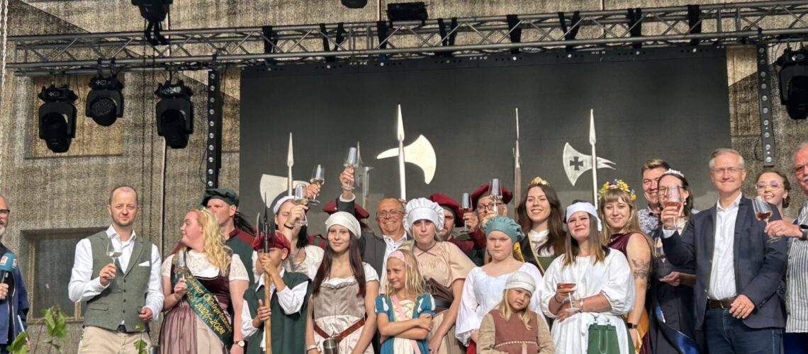 Eine Gruppe von Menschen in historischen Gewändern steht auf einer Bühne