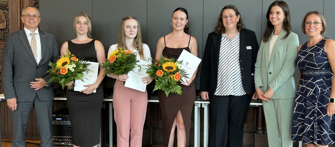 Sieben Personen, zum Teil mit Zeugnissen und Blumen in der Hand, lassen sich fotografieren.