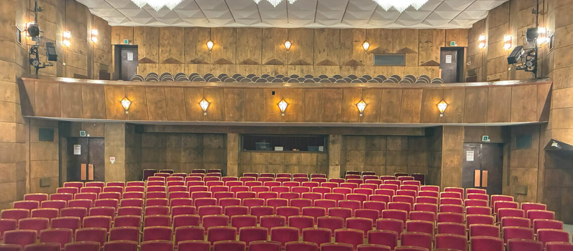 Asicht des Saals im Phönix Theater Wittenberg mit Ansicht von der Bühne nach hinten in den Saal. Rote Theaterstuhlreihen sind zu sehen.