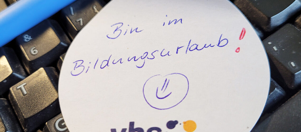 Auf der Tastatur liegt ein Zettel mit der Aufschrift Bildungsurlaub und einem Smiley