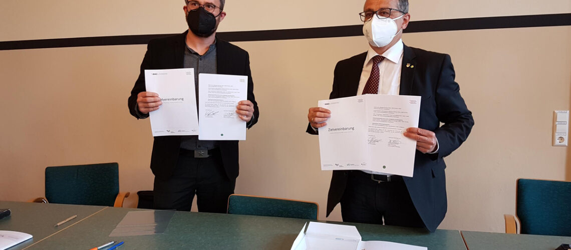 Dr. Jörg Hartmann, stellvertretender Landrat und Dr. Jörg Eulenberger, Leiter des Standorts Süd des BNE-Kompetenzzentrums unterzeichnen die gemeinsame Zielvereinbarung