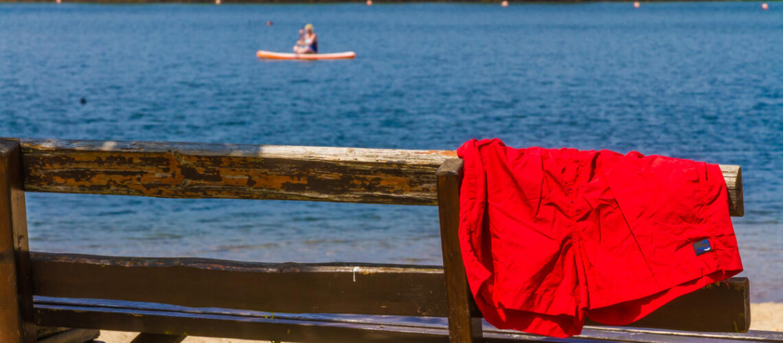 Badesee Dixförda - Bank mit roter Badehose und Blick auf dem See