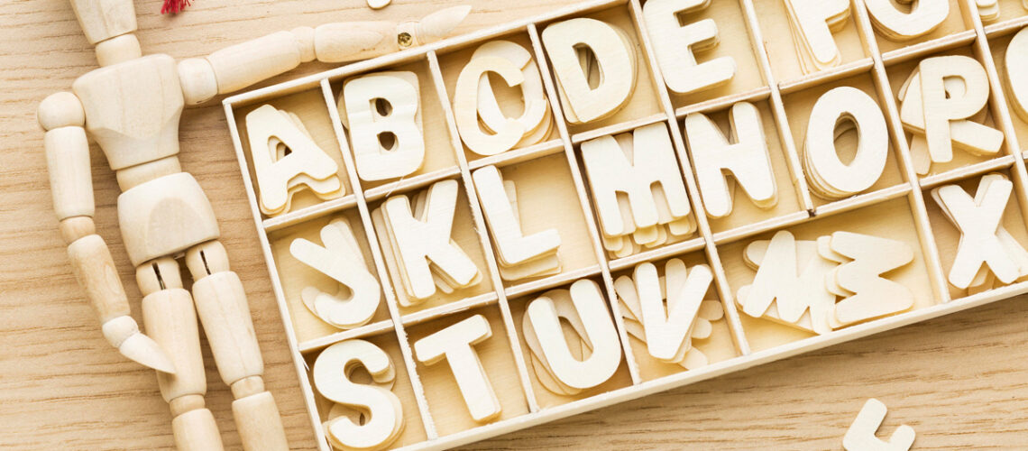 Draufsicht der hölzernen figur mit akademischer kappe und buchstaben