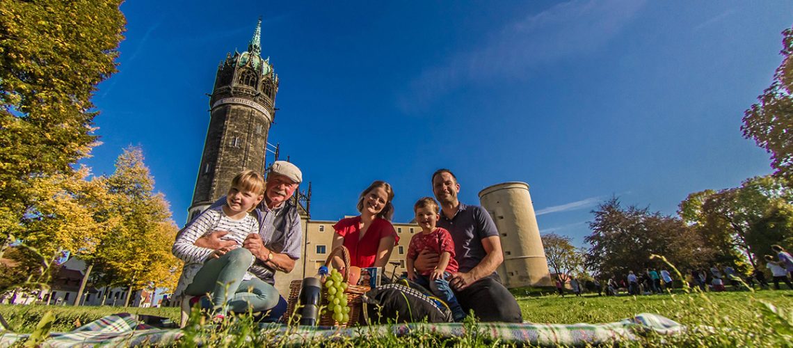 Familie macht ein Picknick vor der Schloßkirche in Wittenberg