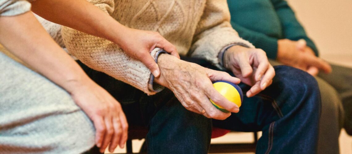 Ein junger Mensch hält die Hand eines älteren Menschen.
