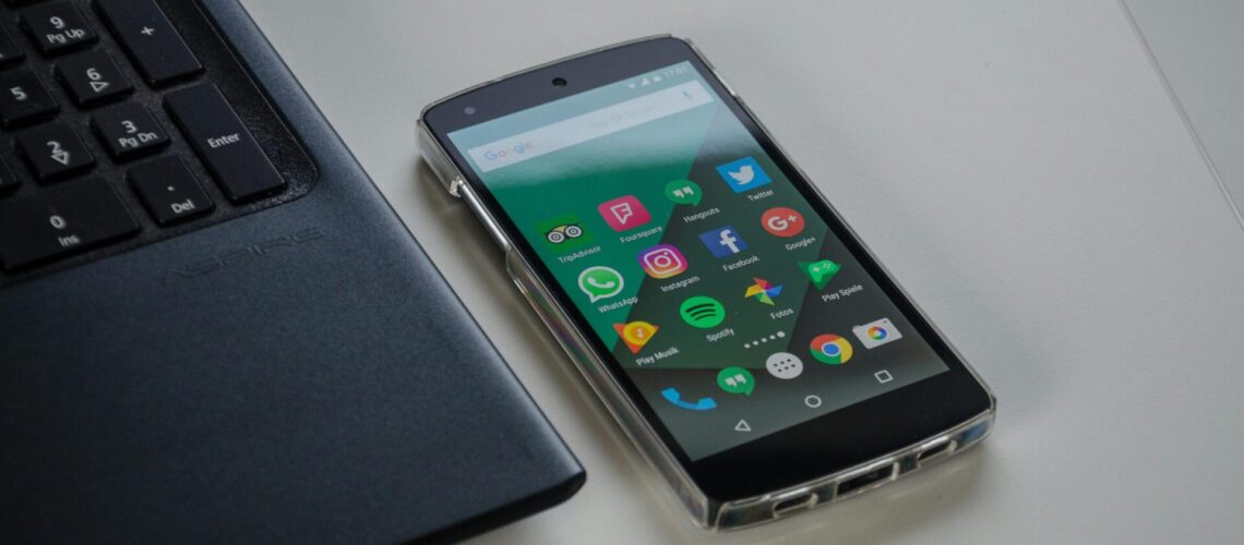 Schwarzes Smartphone liegt neben einem Laptop